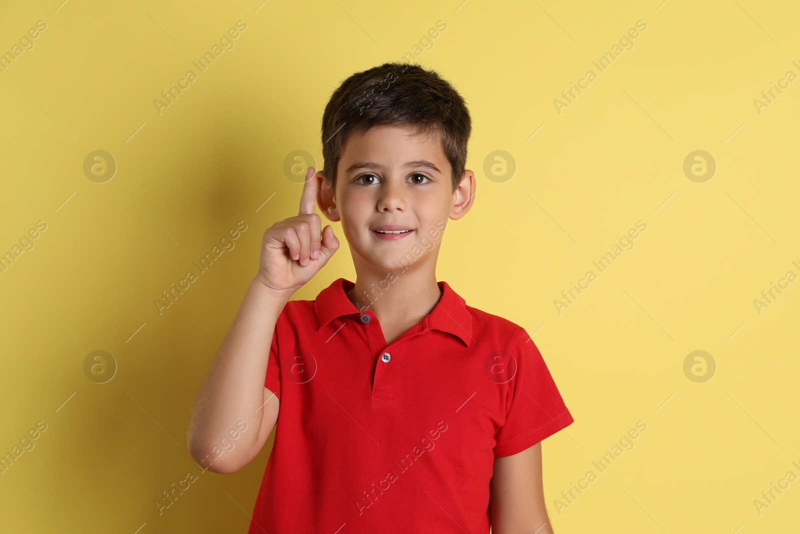 Photo of Portrait of cute little boy on yellow background