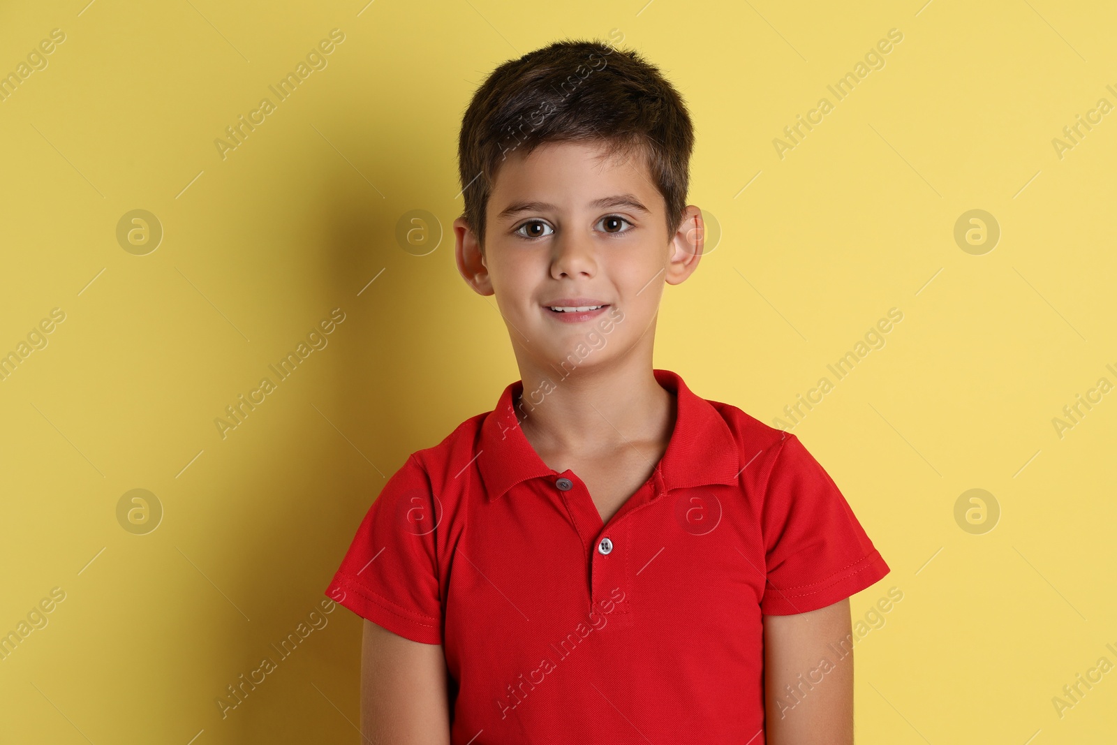 Photo of Portrait of cute little boy on yellow background