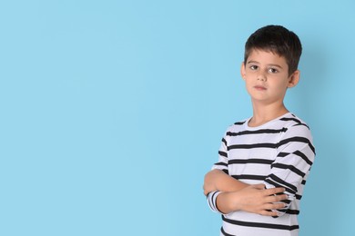 Photo of Portrait of cute little boy on light blue background, space for text