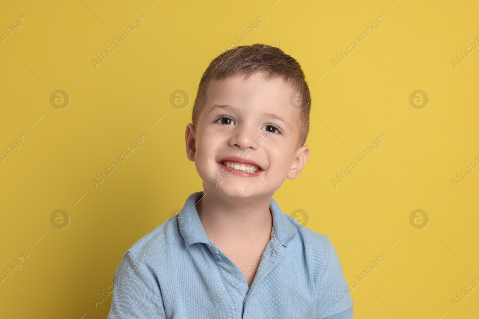 Photo of Portrait of cute little boy on yellow background