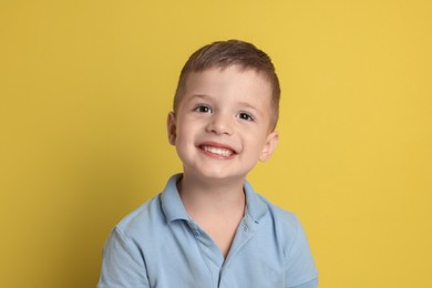 Portrait of cute little boy on yellow background