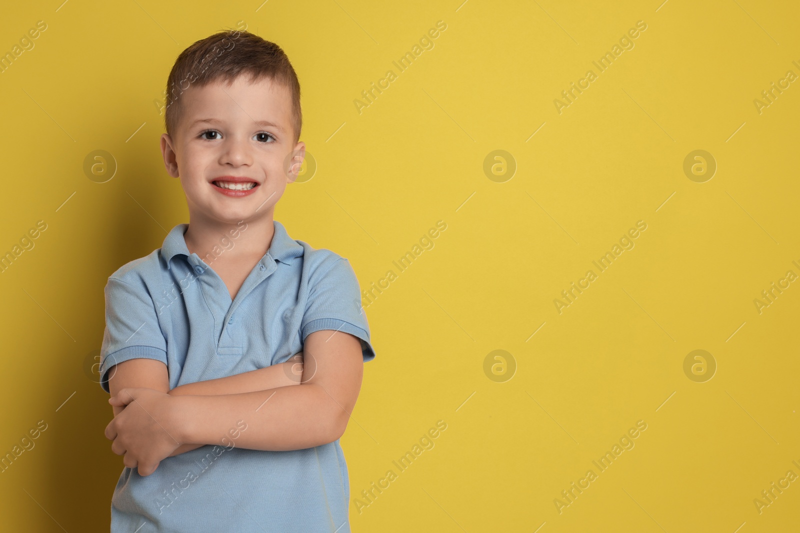 Photo of Portrait of cute little boy on yellow background, space for text