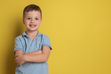 Portrait of cute little boy on yellow background, space for text