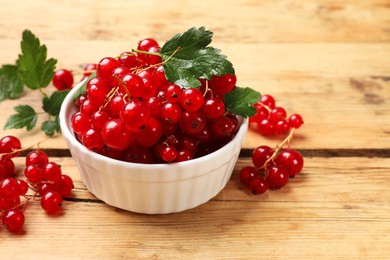 Photo of Fresh red currants and green leaves on wooden table, closeup