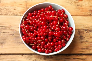 Photo of Fresh red currants in bowl on wooden table, top view