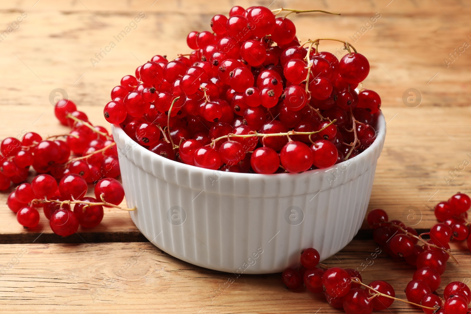 Photo of Fresh red currants in bowl on wooden table, closeup