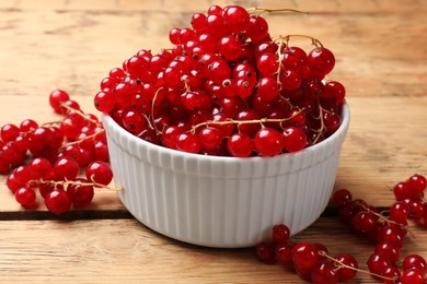 Photo of Fresh red currants in bowl on wooden table, closeup