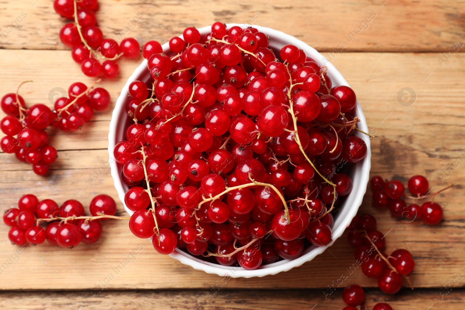 Photo of Fresh red currants in bowl on wooden table, top view