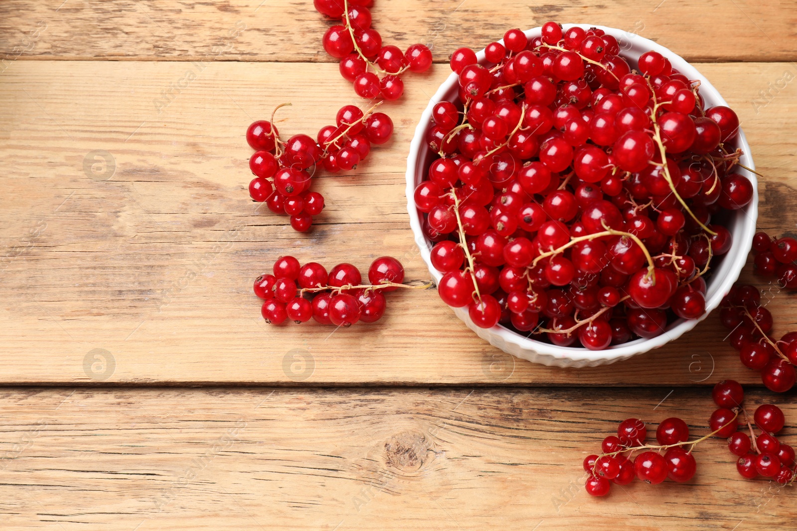 Photo of Fresh red currants in bowl on wooden table, top view. Space for text