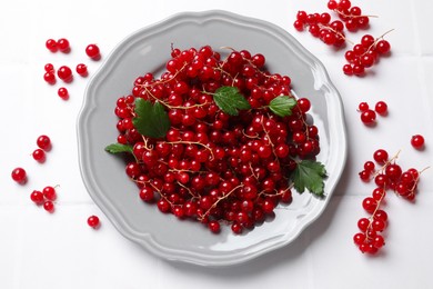 Photo of Fresh red currants and leaves on white table, flat lay