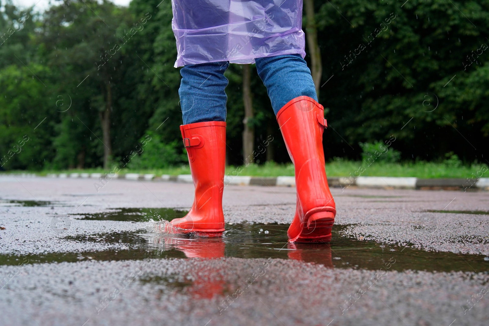 Photo of Woman in red rubber boots walking outdoors, closeup