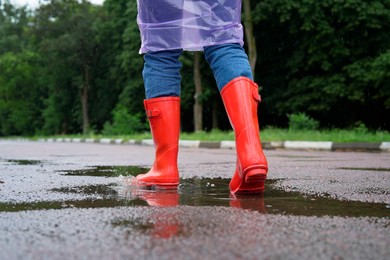 Photo of Woman in red rubber boots walking outdoors, closeup