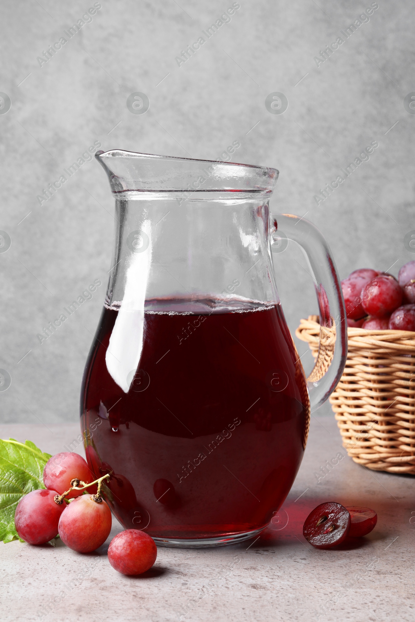 Photo of Ripe grapes and jug of tasty juice on grey table