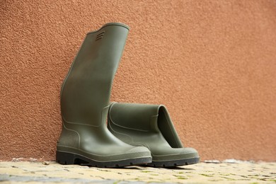 Photo of Grey rubber boots on pavement near wall outdoors