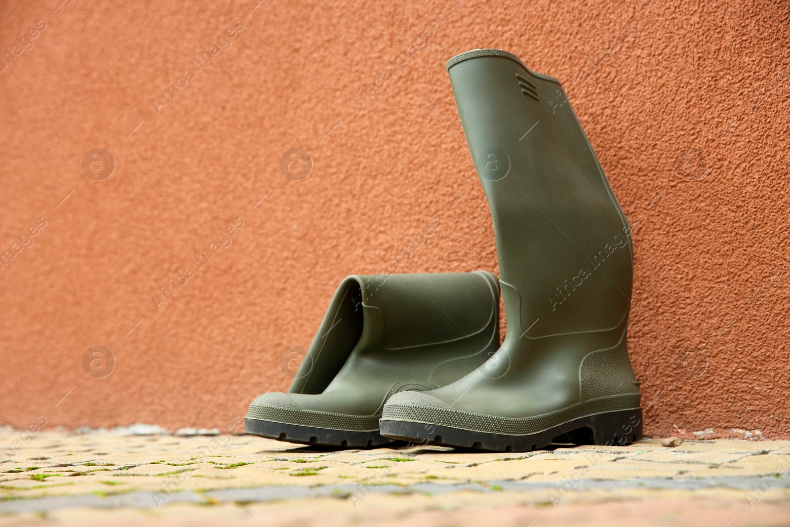 Photo of Grey rubber boots on pavement near wall outdoors