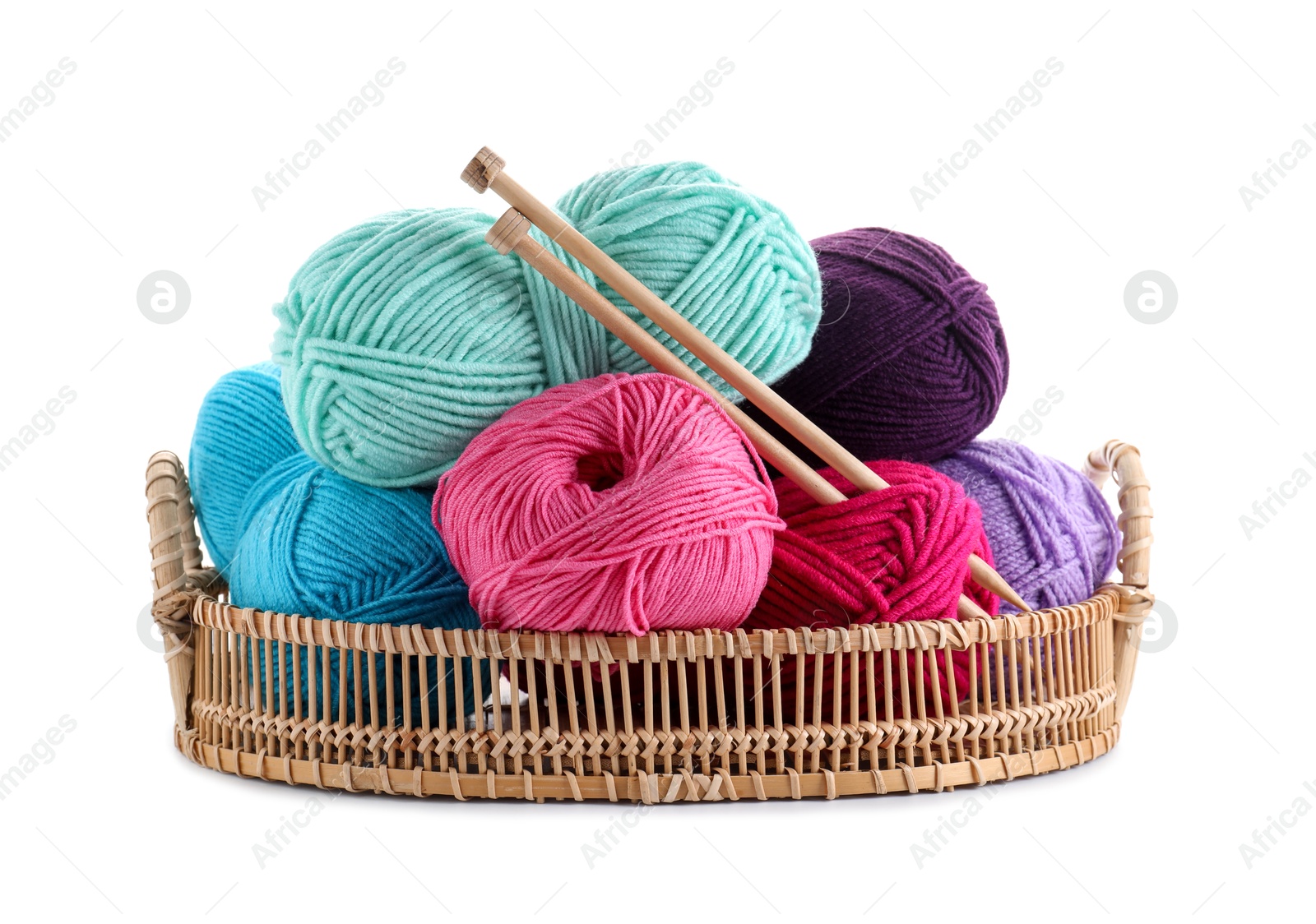 Photo of Many bright yarns and knitting needles in wicker basket isolated on white