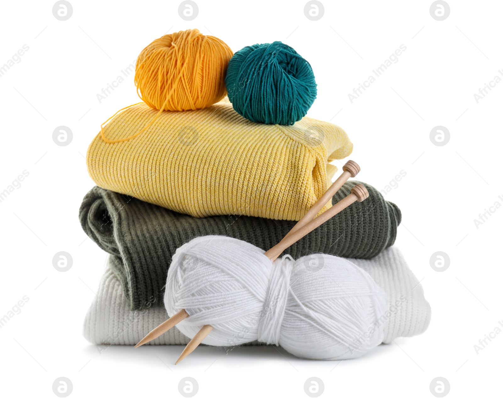 Photo of Different yarns, knitting needles and stack of sweaters isolated on white