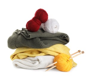 Photo of Different yarns, knitting needles and stack of sweaters isolated on white