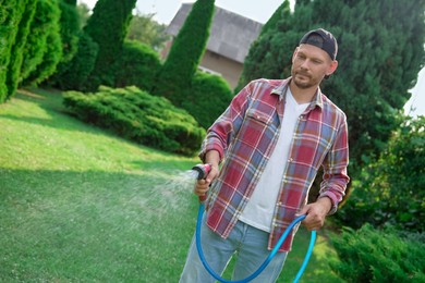 Photo of Man watering lawn with hose in backyard, space for text