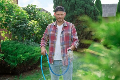 Man watering lawn with hose in backyard