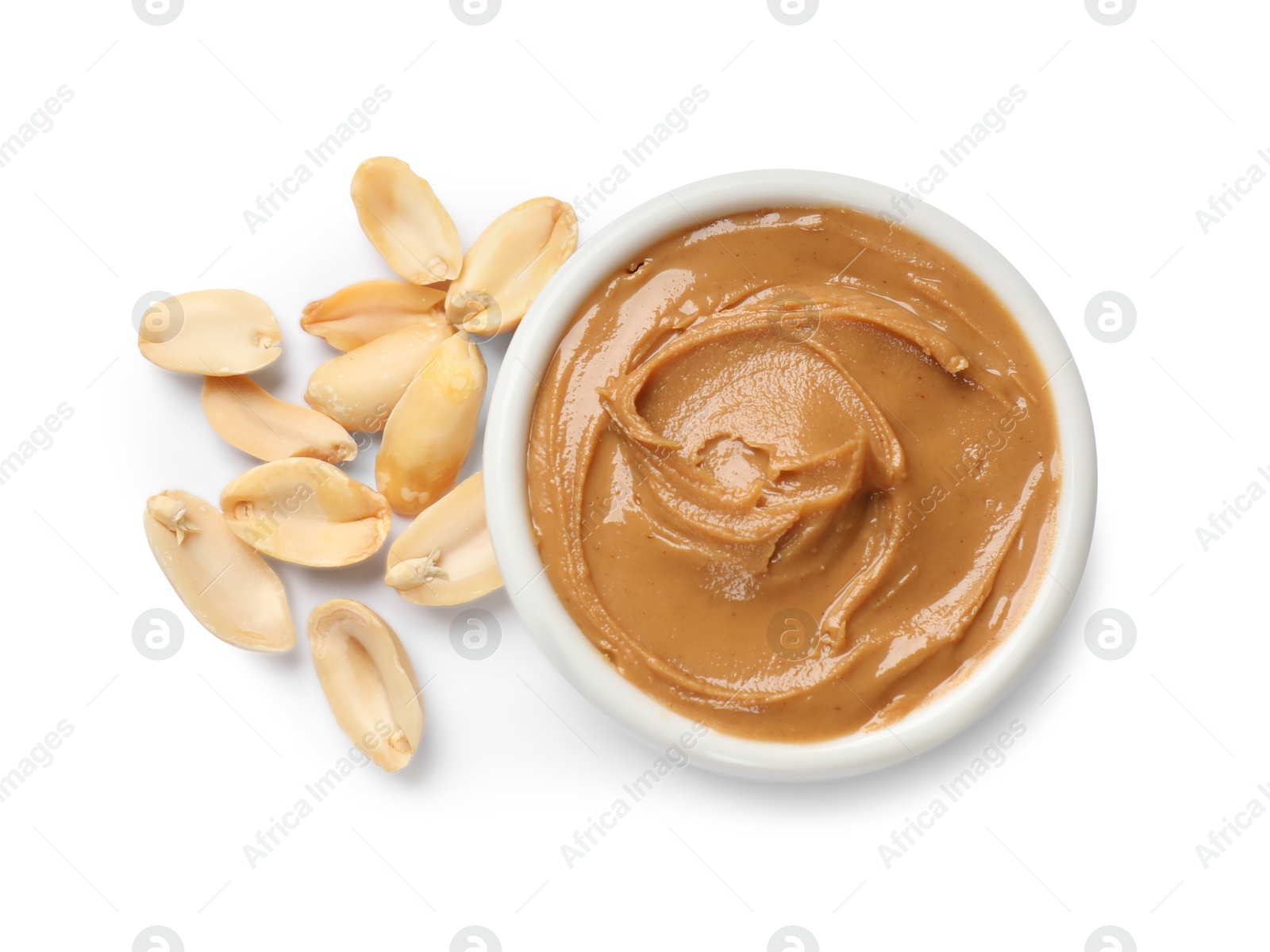 Photo of Tasty peanut butter in bowl and groundnuts isolated on white, top view