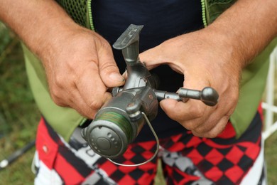 Photo of Senior fisherman holding fishing equipment outdoors, closeup