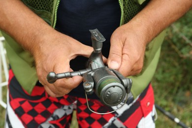 Senior fisherman holding fishing equipment outdoors, closeup