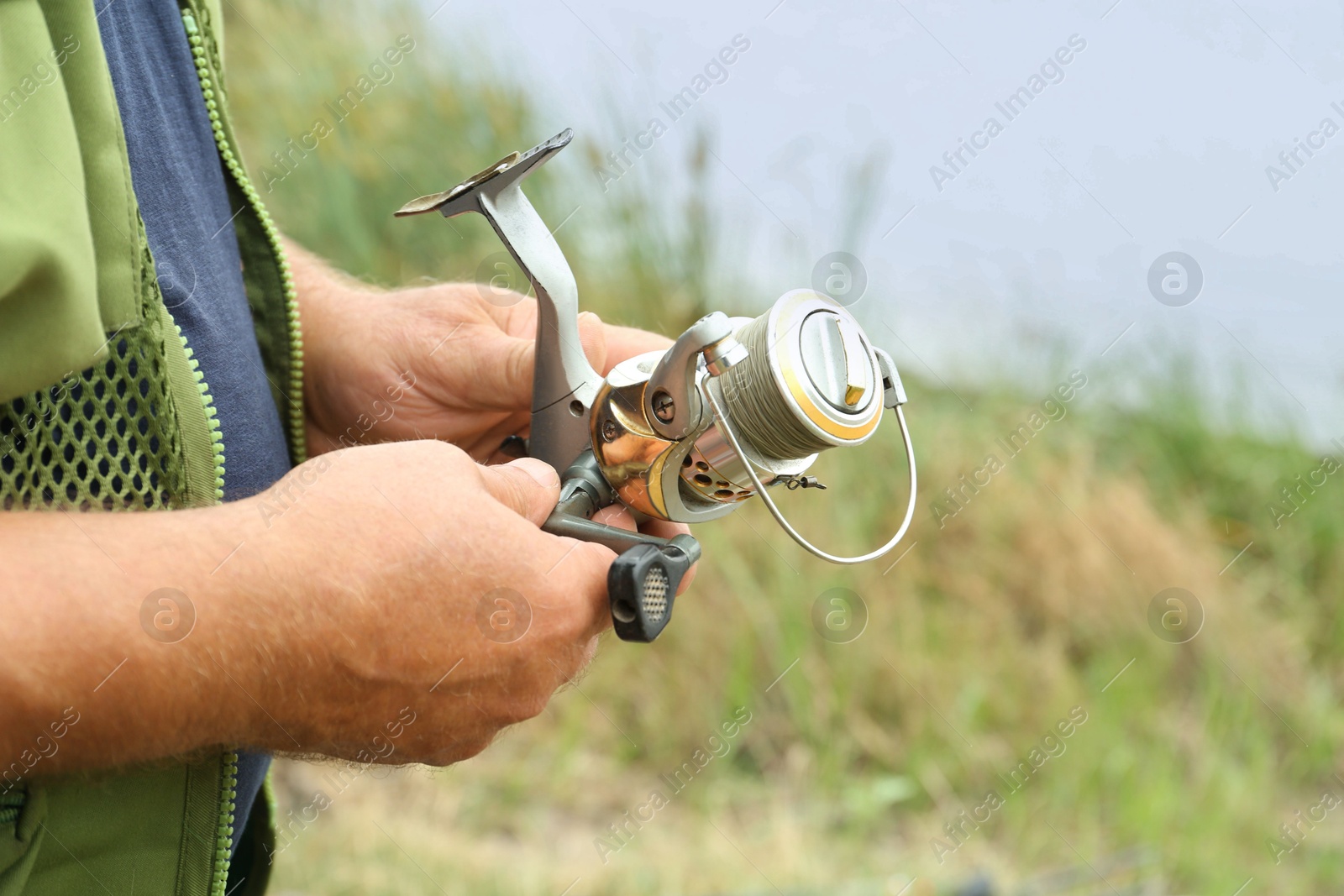 Photo of Senior fisherman holding fishing equipment outdoors, closeup