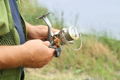 Photo of Senior fisherman holding fishing equipment outdoors, closeup