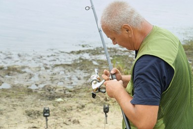 Fisherman with rod fishing near lake at summer