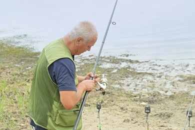 Photo of Fisherman with rod fishing near lake at summer