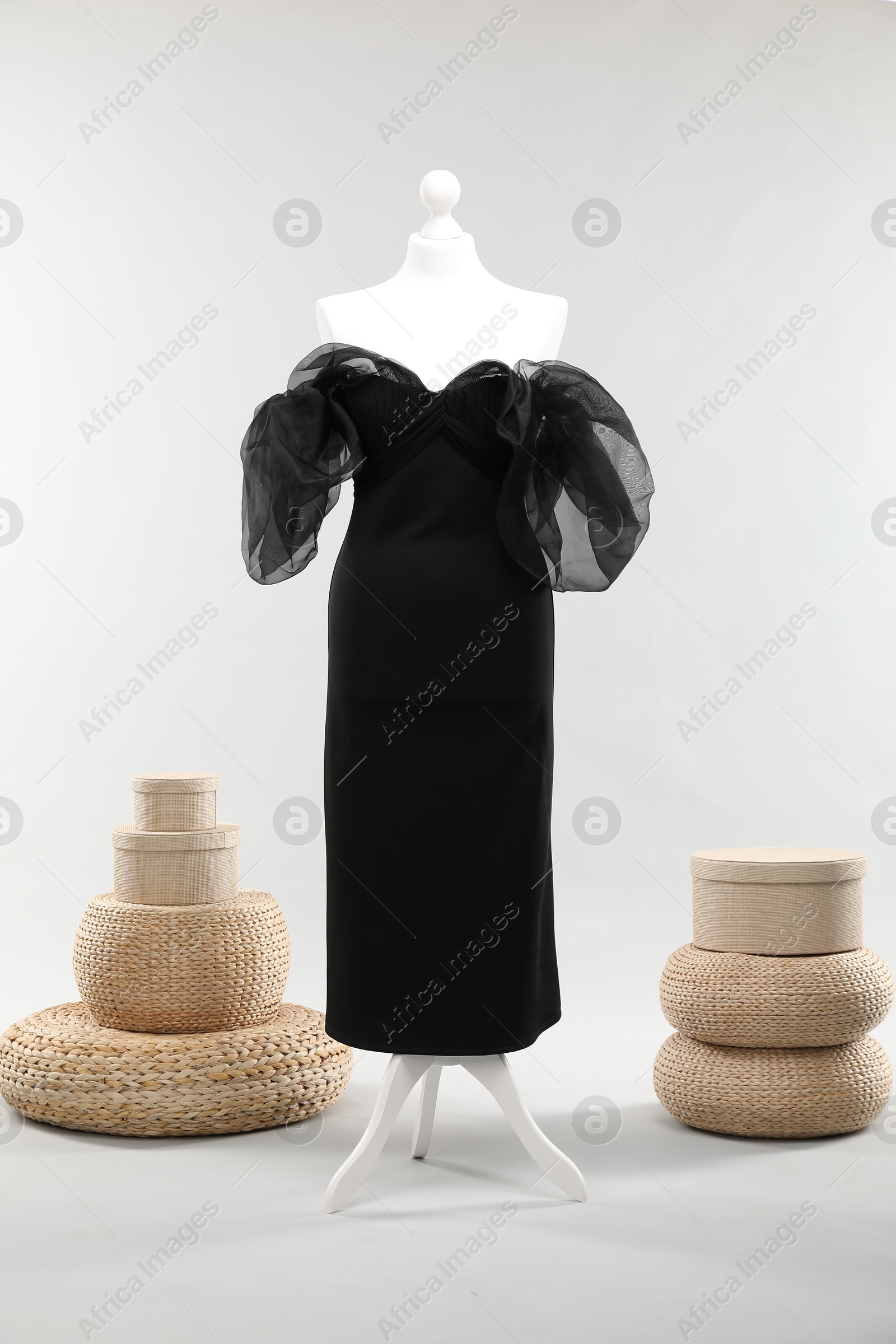 Photo of One female mannequin with dress, poufs and boxes on light background