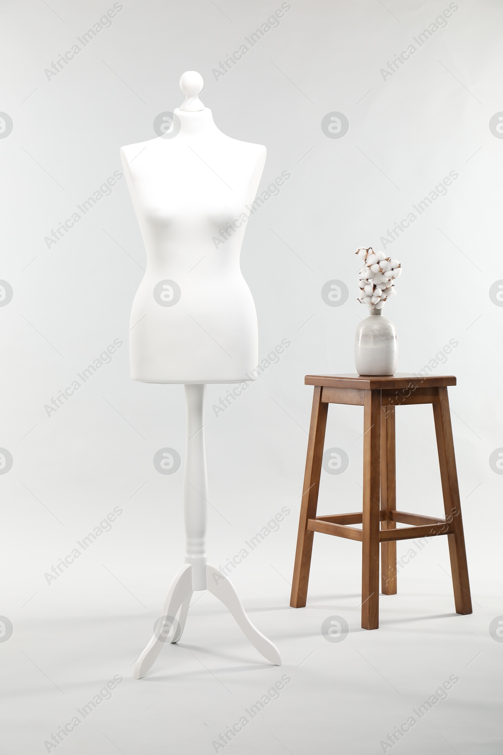 Photo of One female mannequin, stool and cotton flowers on light background