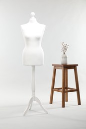 One female mannequin, stool and cotton flowers on light background