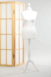 Photo of One female mannequin and folding screen on light background