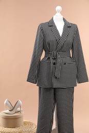 Female mannequin with suit, pouf and shoes on beige background