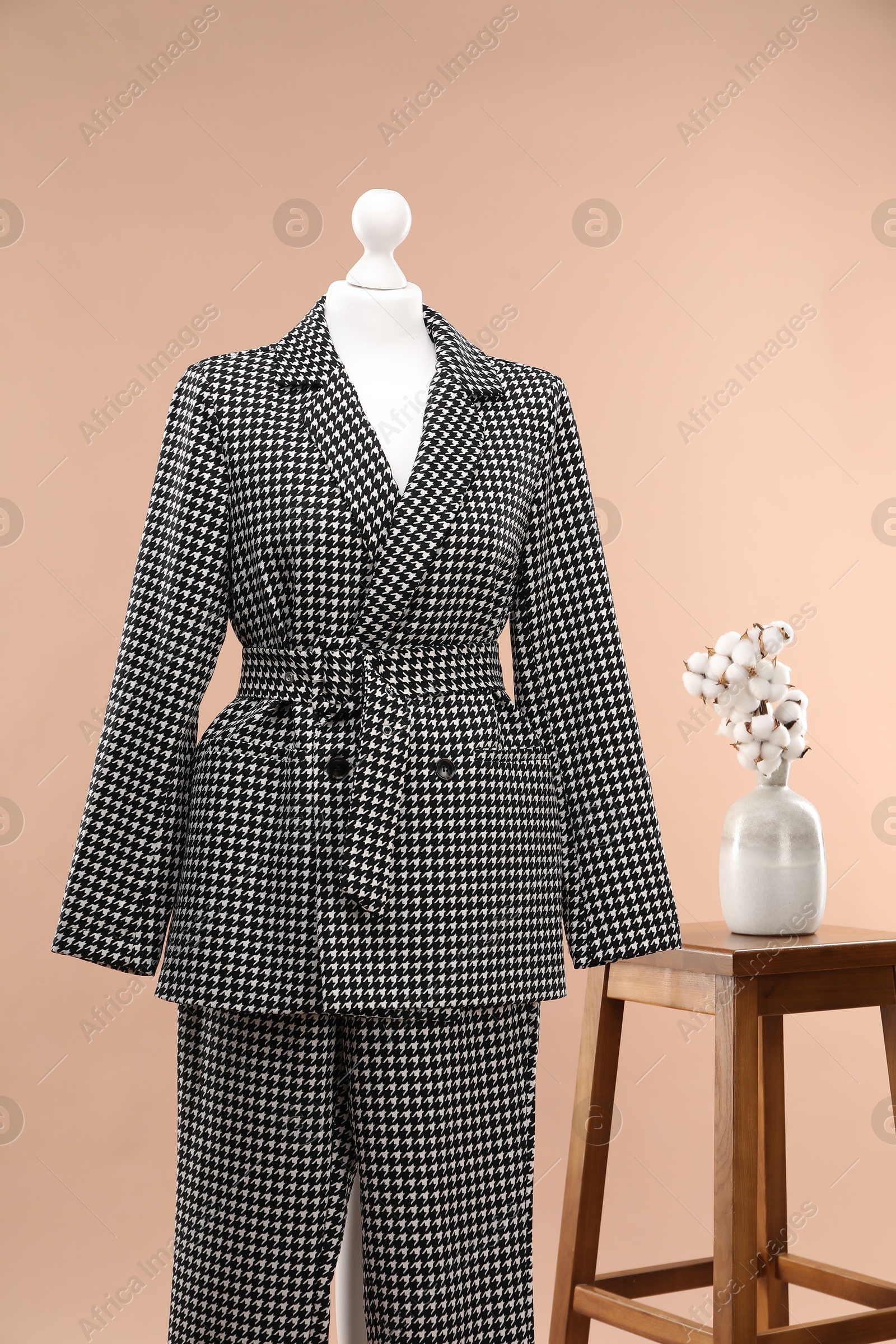 Photo of Female mannequin with suit, stool and cotton flowers on beige background