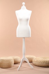 Photo of One female mannequin and poufs on beige background