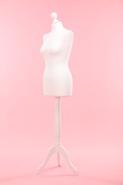 One female mannequin on stand against pink background