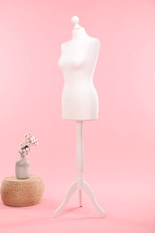 Photo of Female mannequin, pouf and vase with cotton flowers on pink background