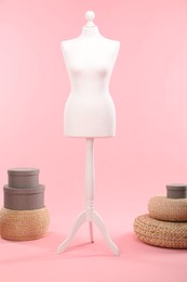 Female mannequin, poufs and boxes on pink background