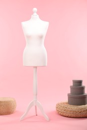 Female mannequin, poufs and boxes on pink background