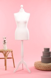 Female mannequin, pouf, boxes, stool and vase with cotton flowers on pink background