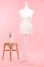 Photo of Female mannequin, stool and vase with cotton flowers on pink background