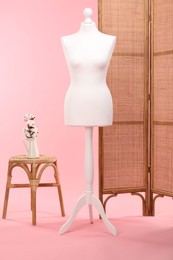 Photo of Female mannequin, folding screen, stool and vase with cotton flowers on pink background