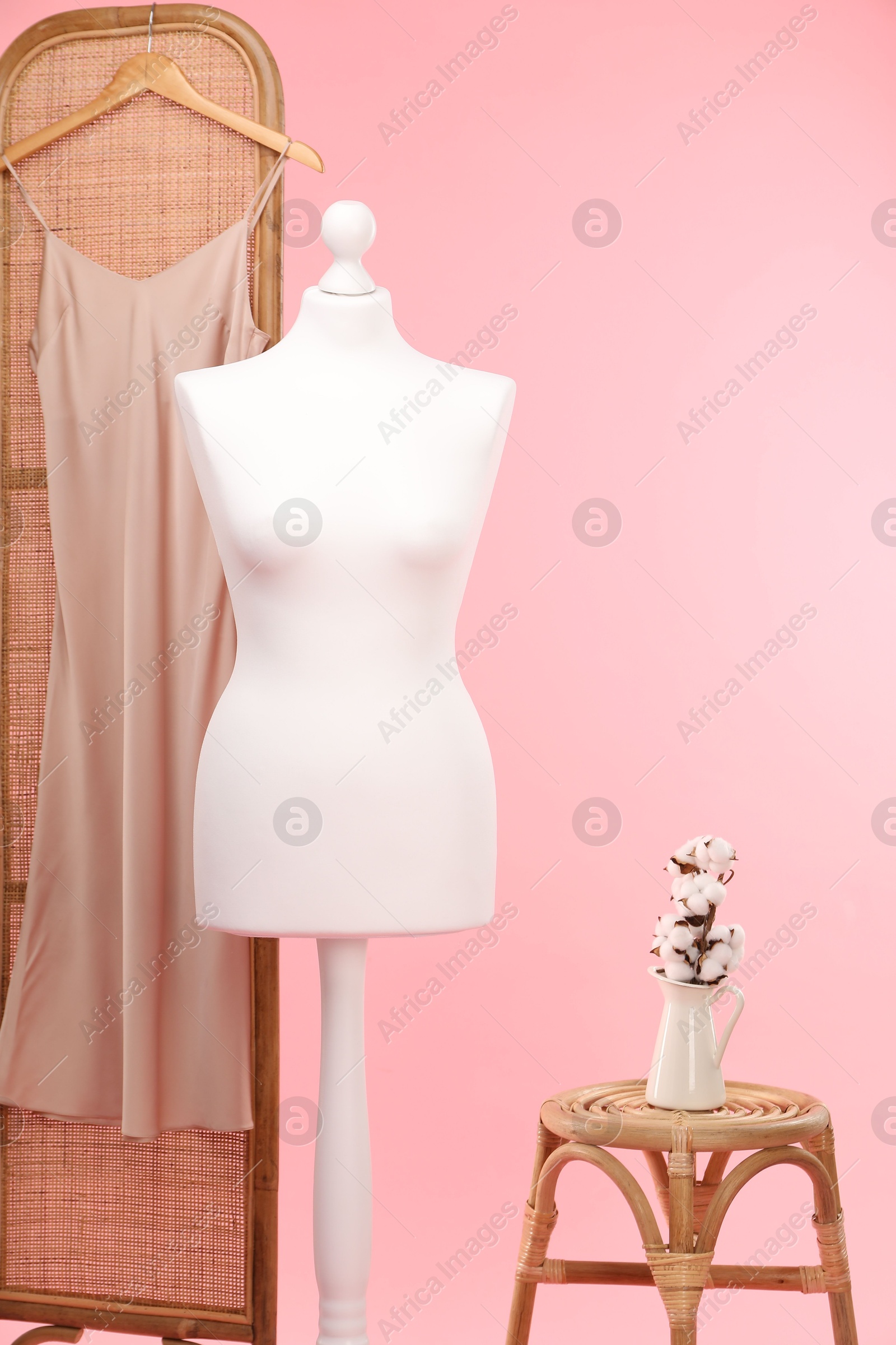 Photo of Female mannequin, folding screen with dress, stool and cotton flowers on pink background