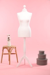 Photo of Female mannequin, boxes, stool and vase with cotton flowers on pink background