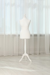 One female mannequin on stand near window indoors