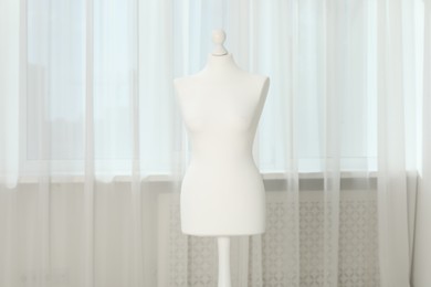 Photo of One female mannequin on stand near window indoors