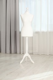 Photo of One female mannequin on stand near window indoors